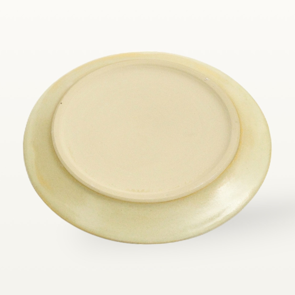 Bodenansicht eines cremefarbenen Keramik Tellers, zeigt den Kontrast zwischen farbiger Glasur und unglasiertem Boden