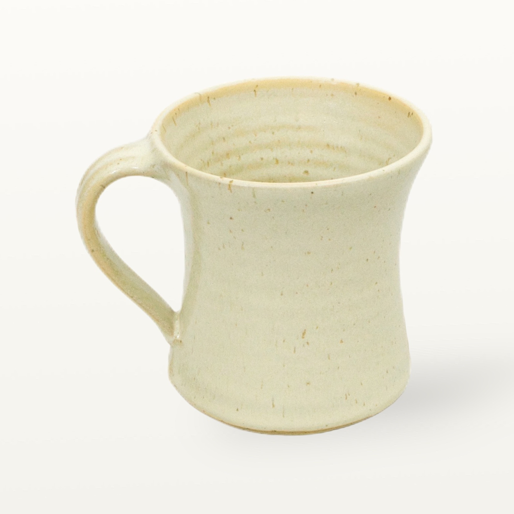 Seitenansicht einer cremefarbenen Töpfertasse mit handgeformtem Henkel aus regionaler Herstellung.